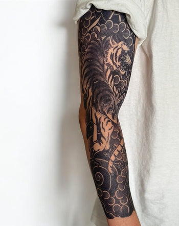 A semi-permanent tattoo featuring a Japanese tiger style design on a full sleeve, predominantly black in color with intricate patterns.
